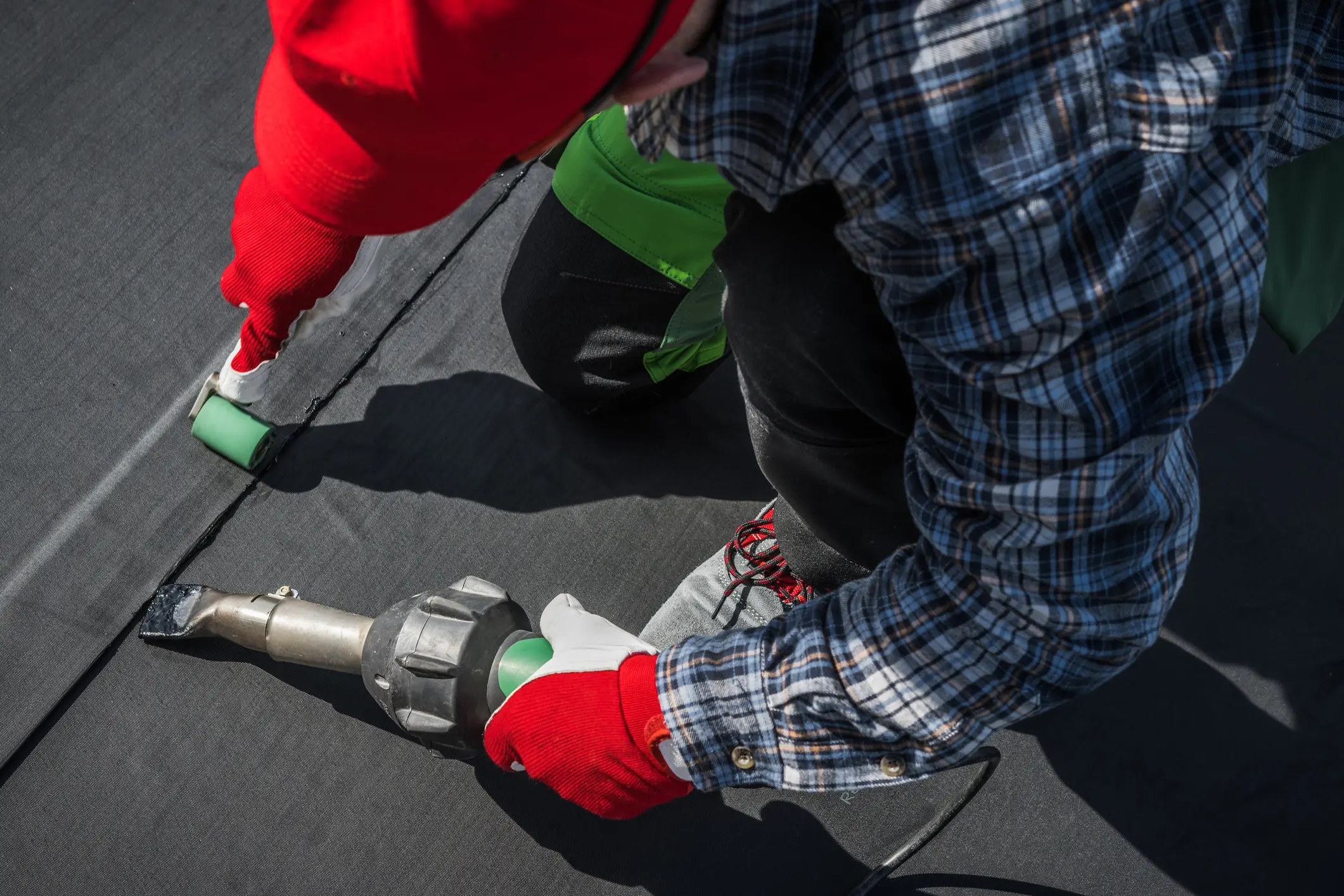 Child in red gloves using a drill on a black surface.