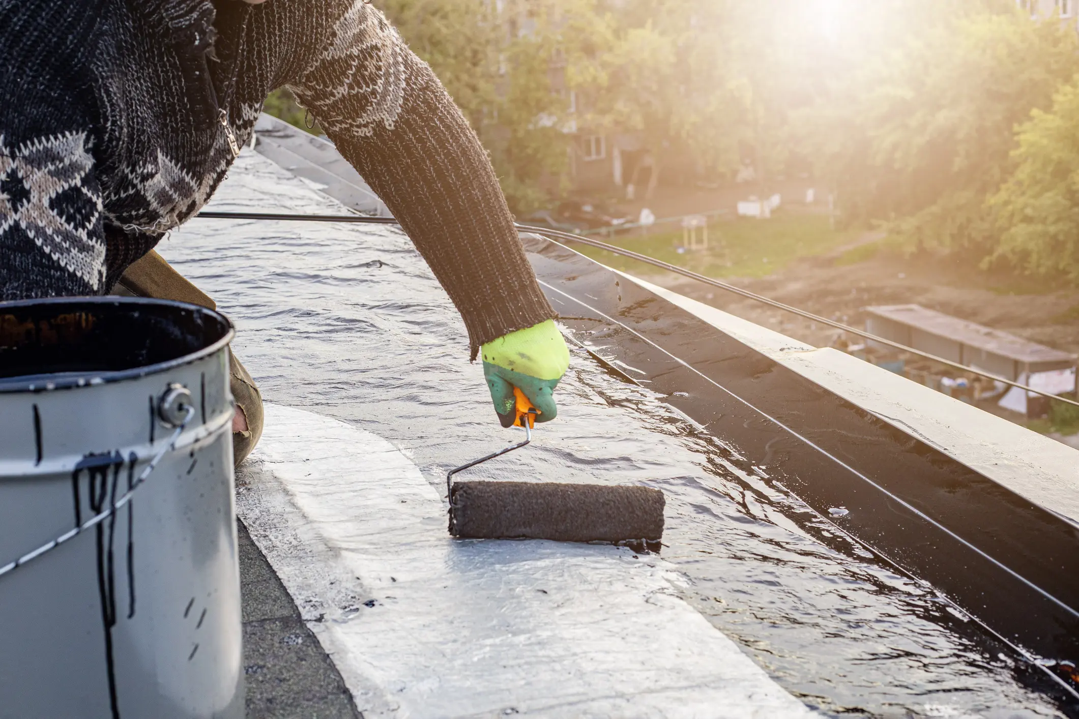 Roofer using roller for waterproofing