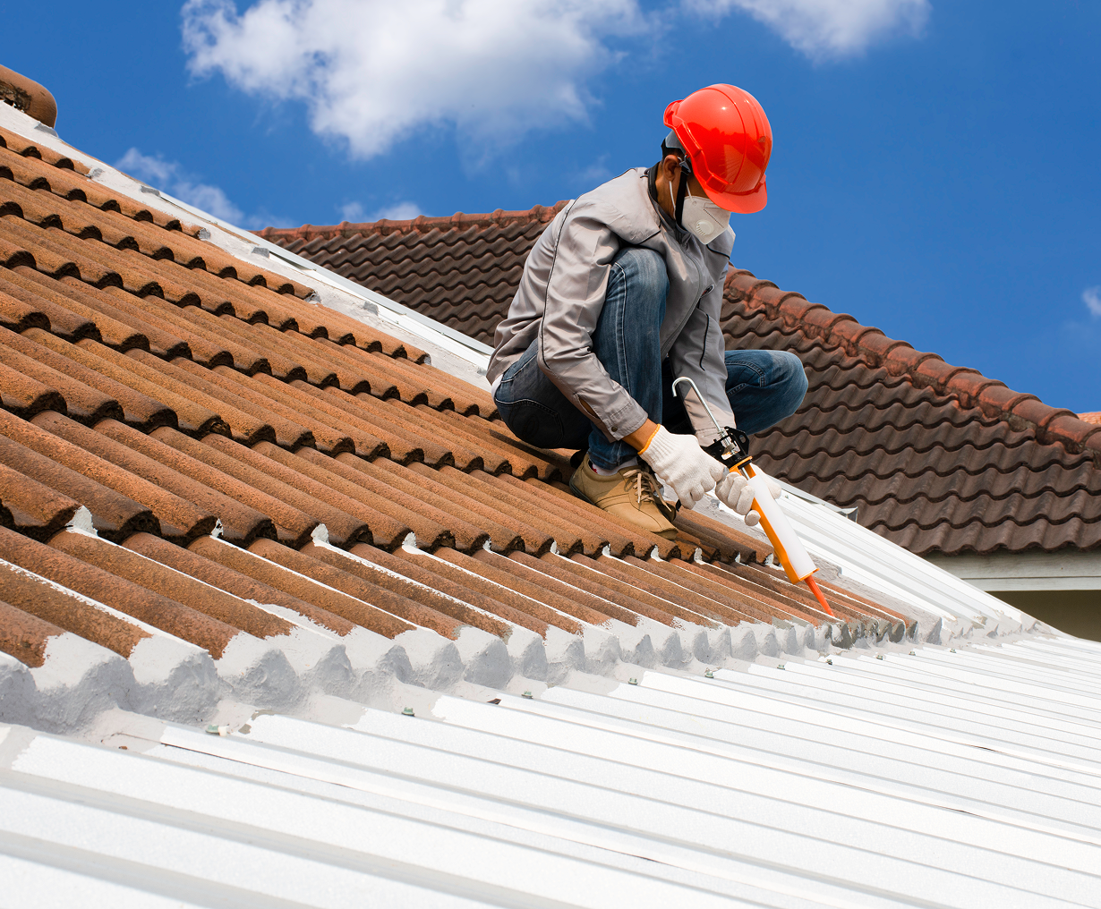 Worker in helmet repairing roof tiles