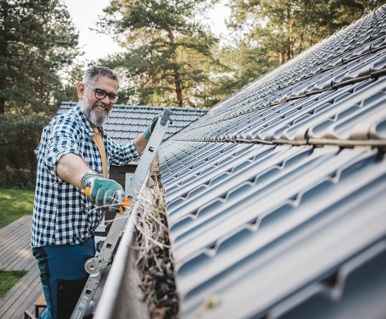 Man cleaning roof gutters with a ladder