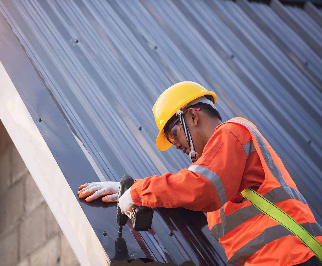 Worker installing metal roof with drill