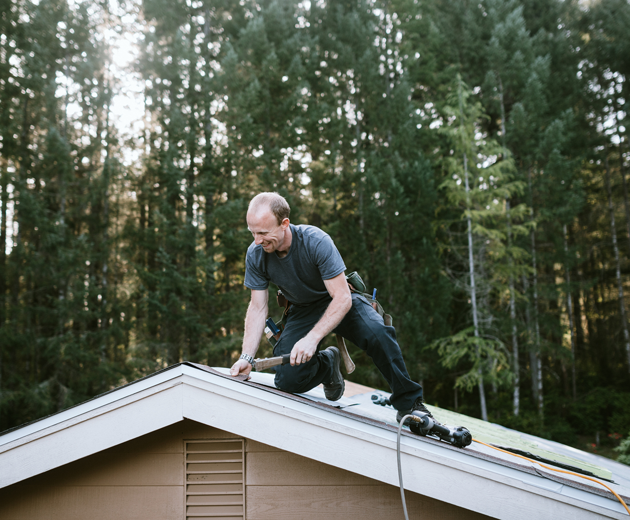 Man working on roof in forest setting.