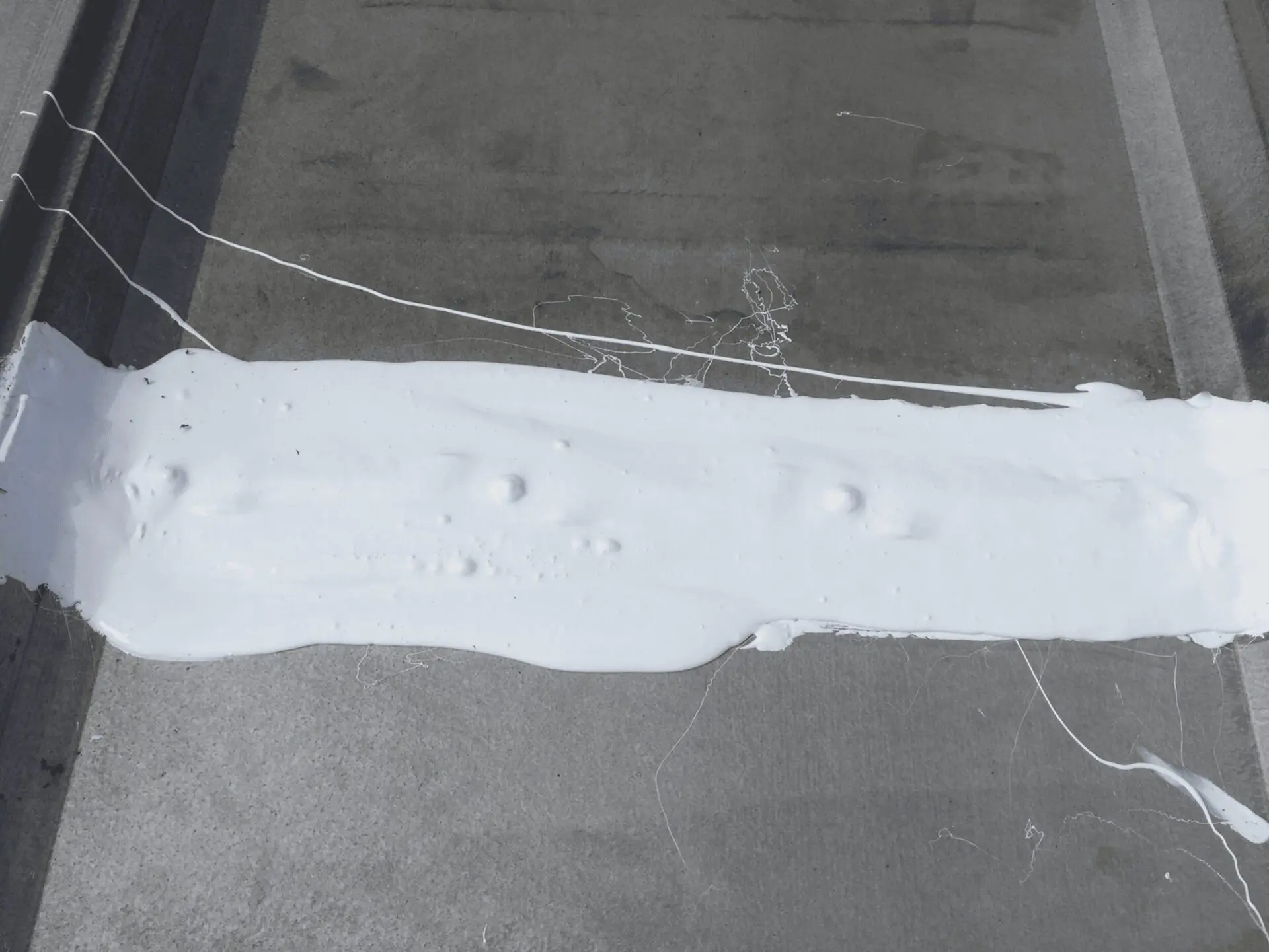 A white paint strip on a gray surface with wires around it.