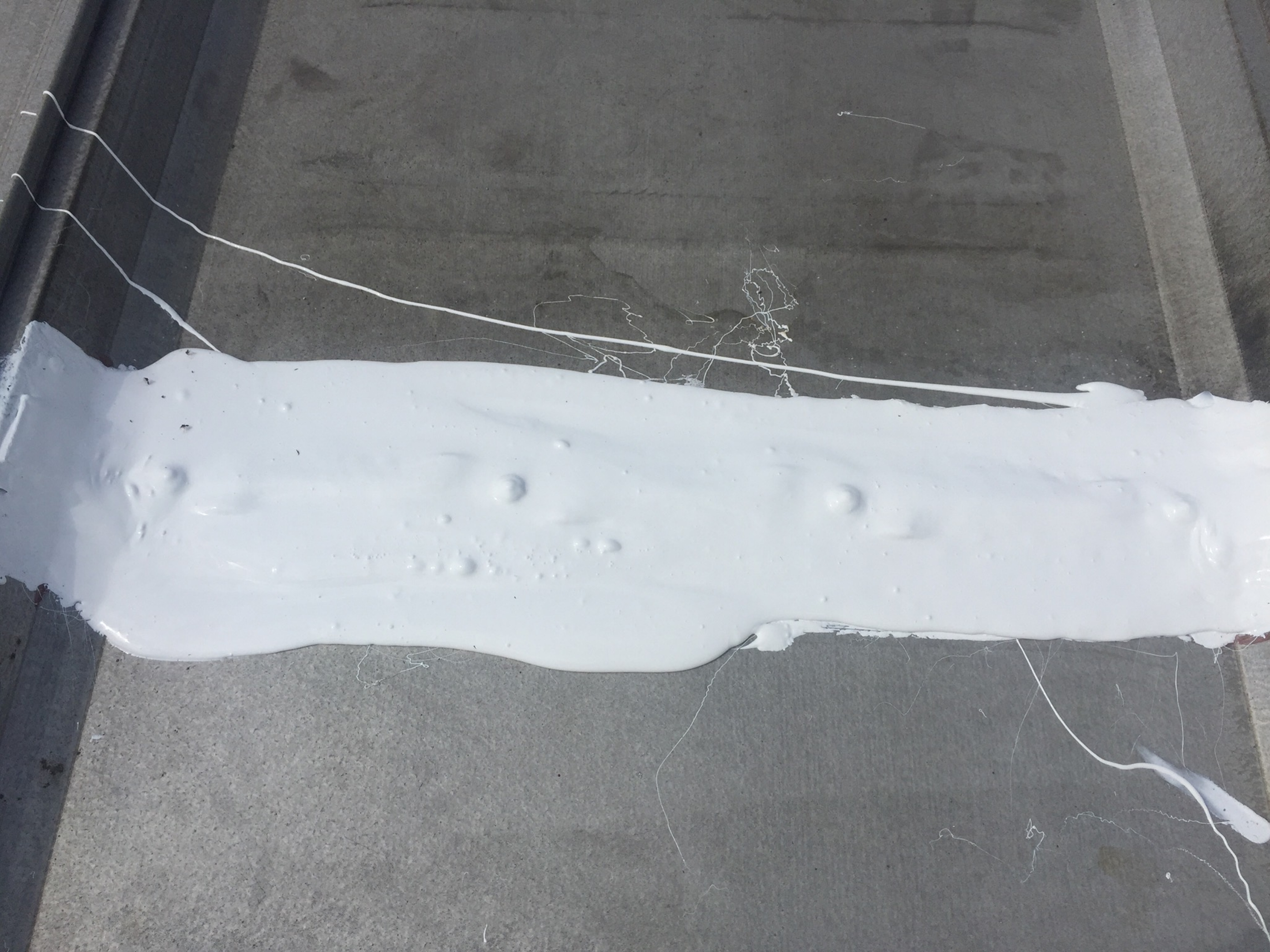 A white paint strip on a gray surface with wires around it.