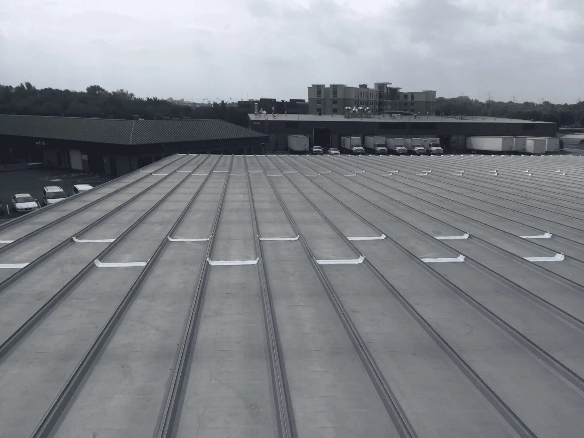 Metal roof with evenly spaced white rectangular objects under a cloudy sky.