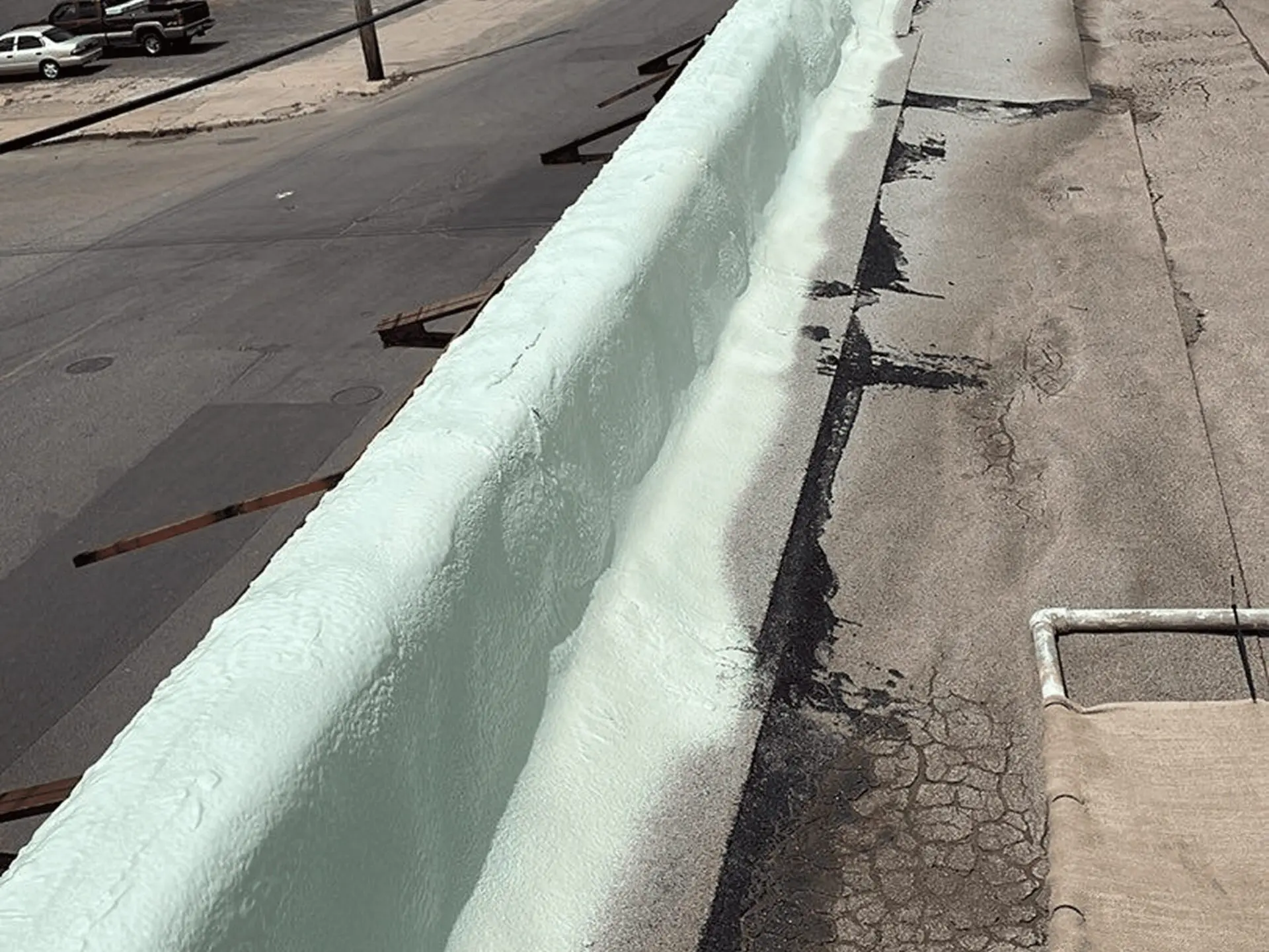 Long white foam strip applied on rooftop surface.