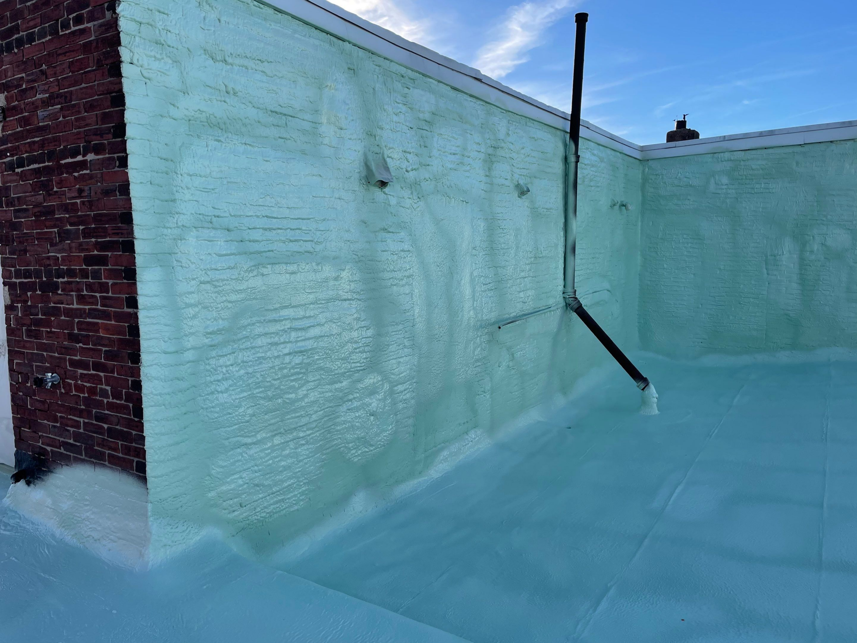 A rooftop with green waterproof coating and a drain pipe.