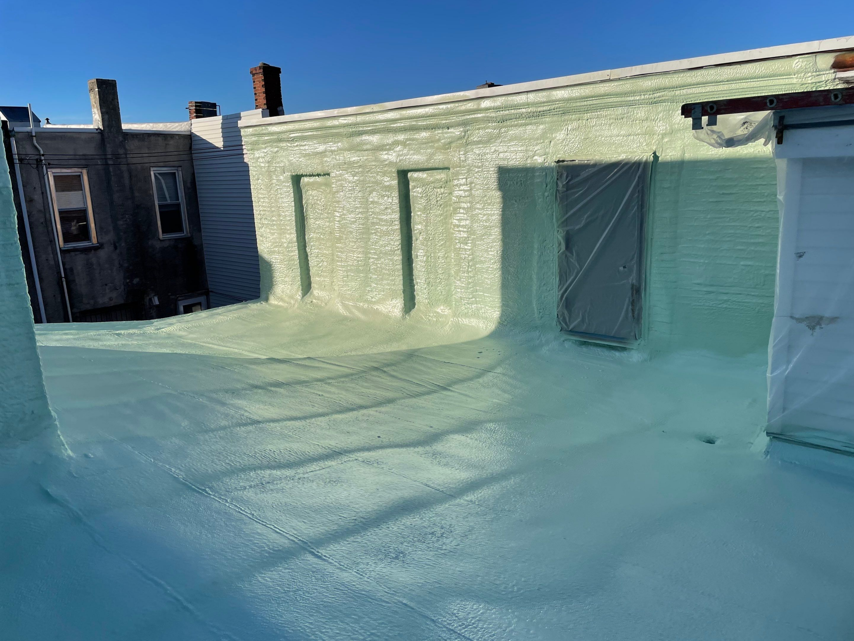 A flat rooftop covered with white reflective coating under a clear blue sky.