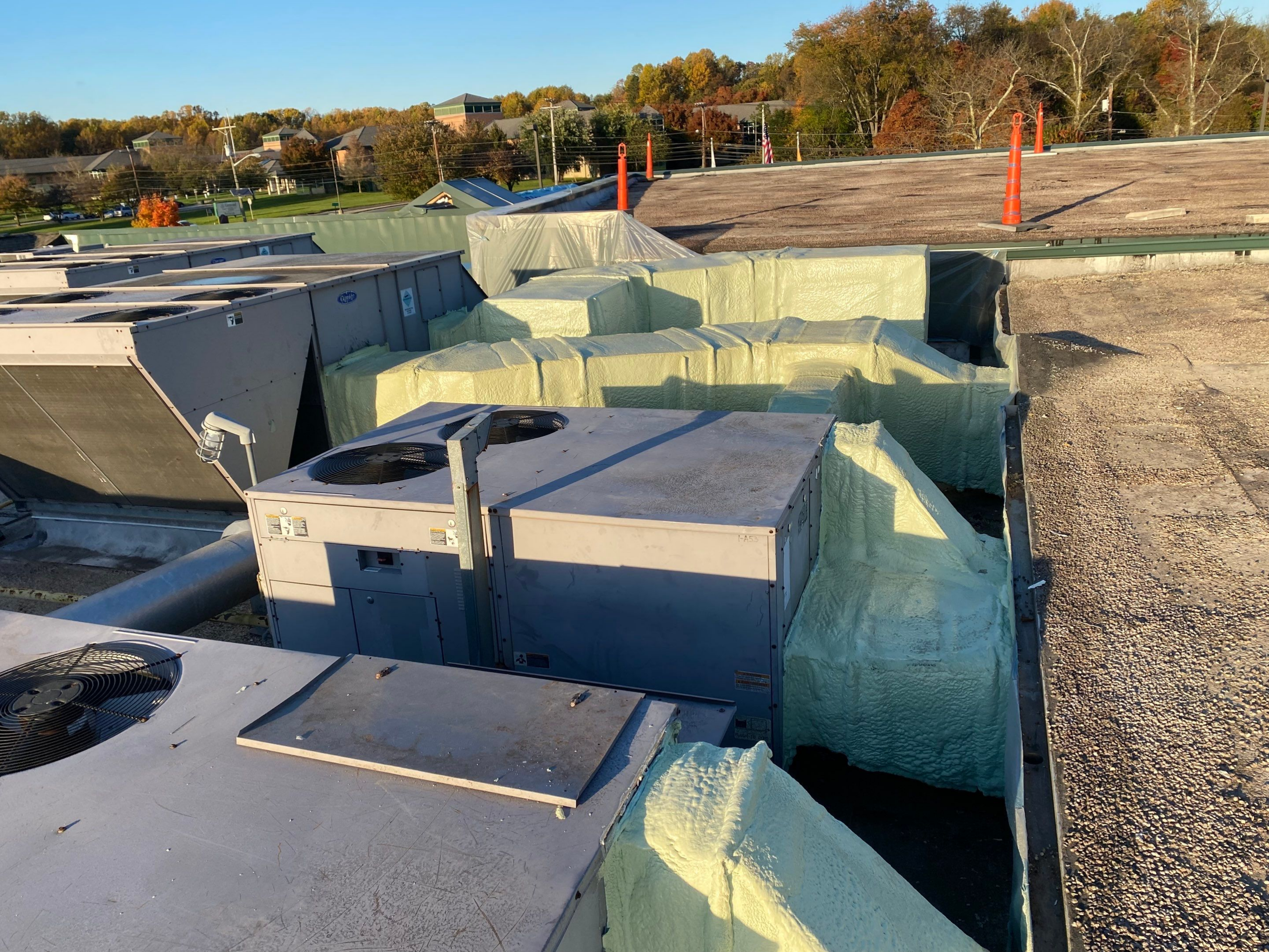 Rooftop with various HVAC units and ducts under evening light.