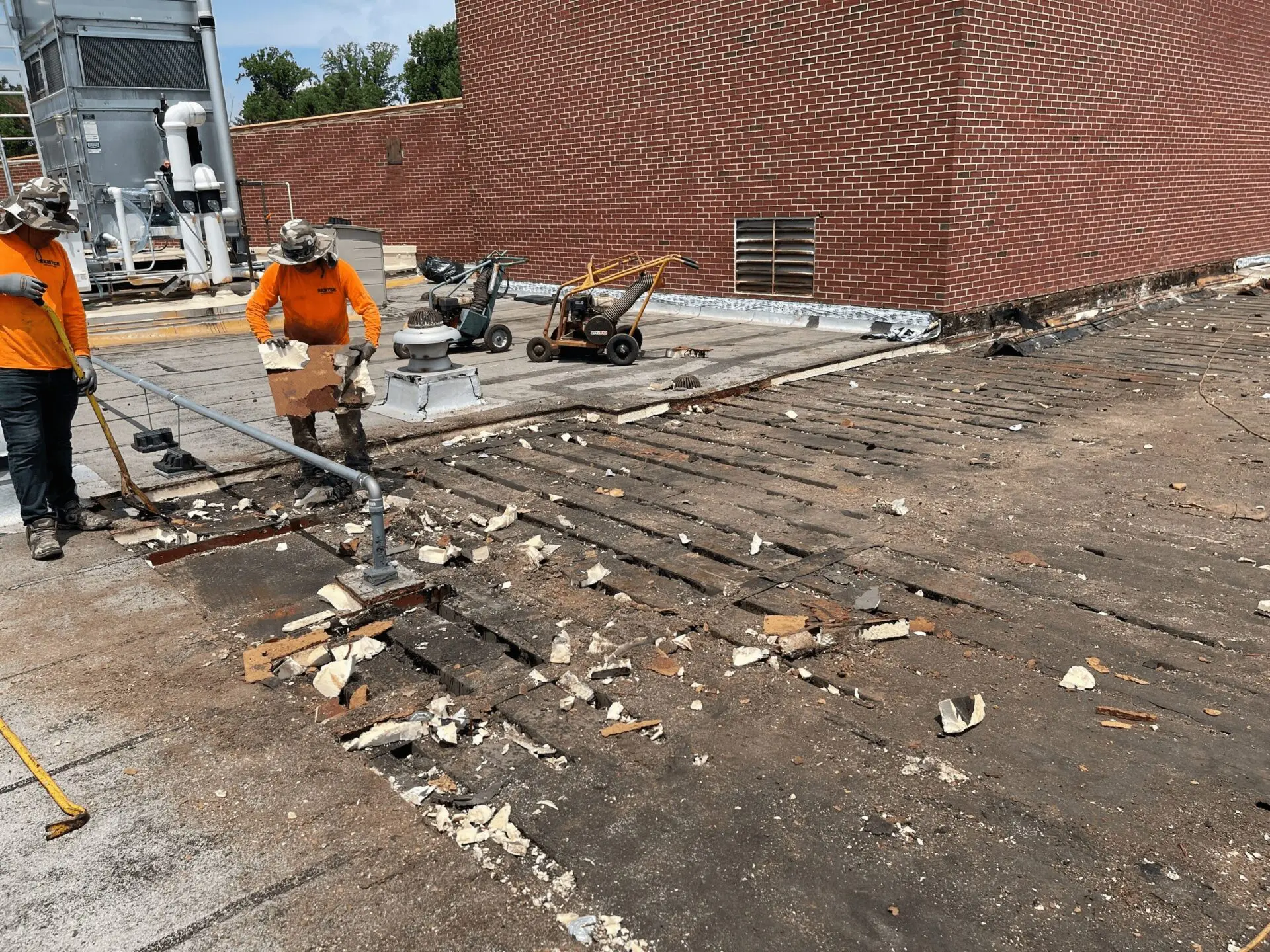 Worker demolishing old bricks on a rooftop with a sledgehammer.