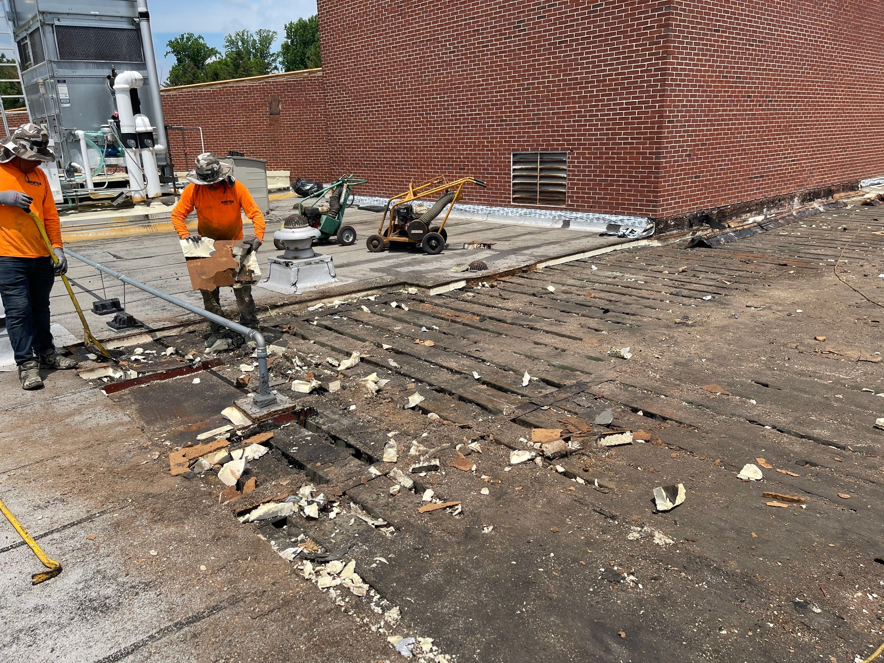 Worker demolishing old bricks on a rooftop with a sledgehammer.