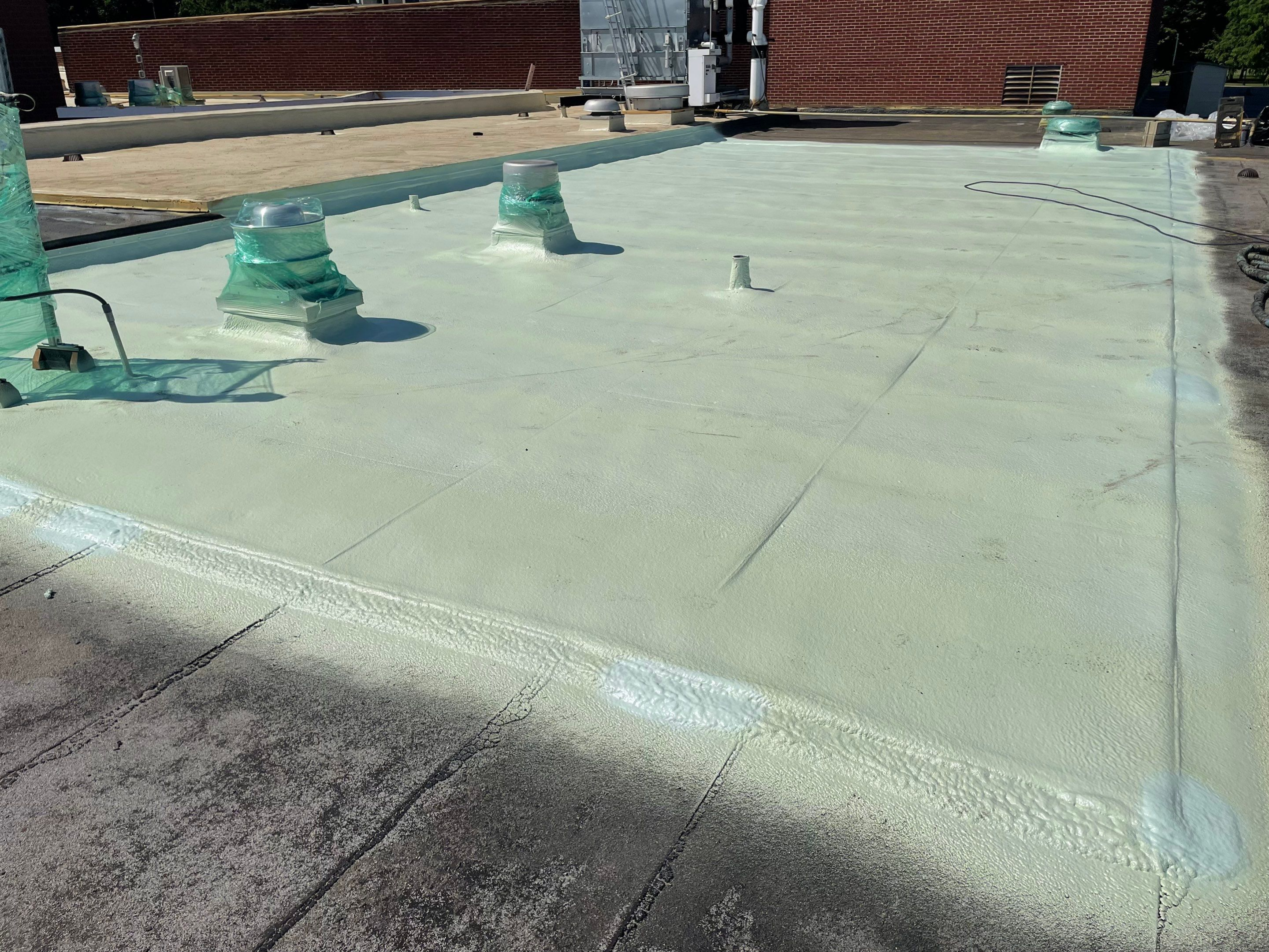 A flat rooftop with multiple vents and a light coating.