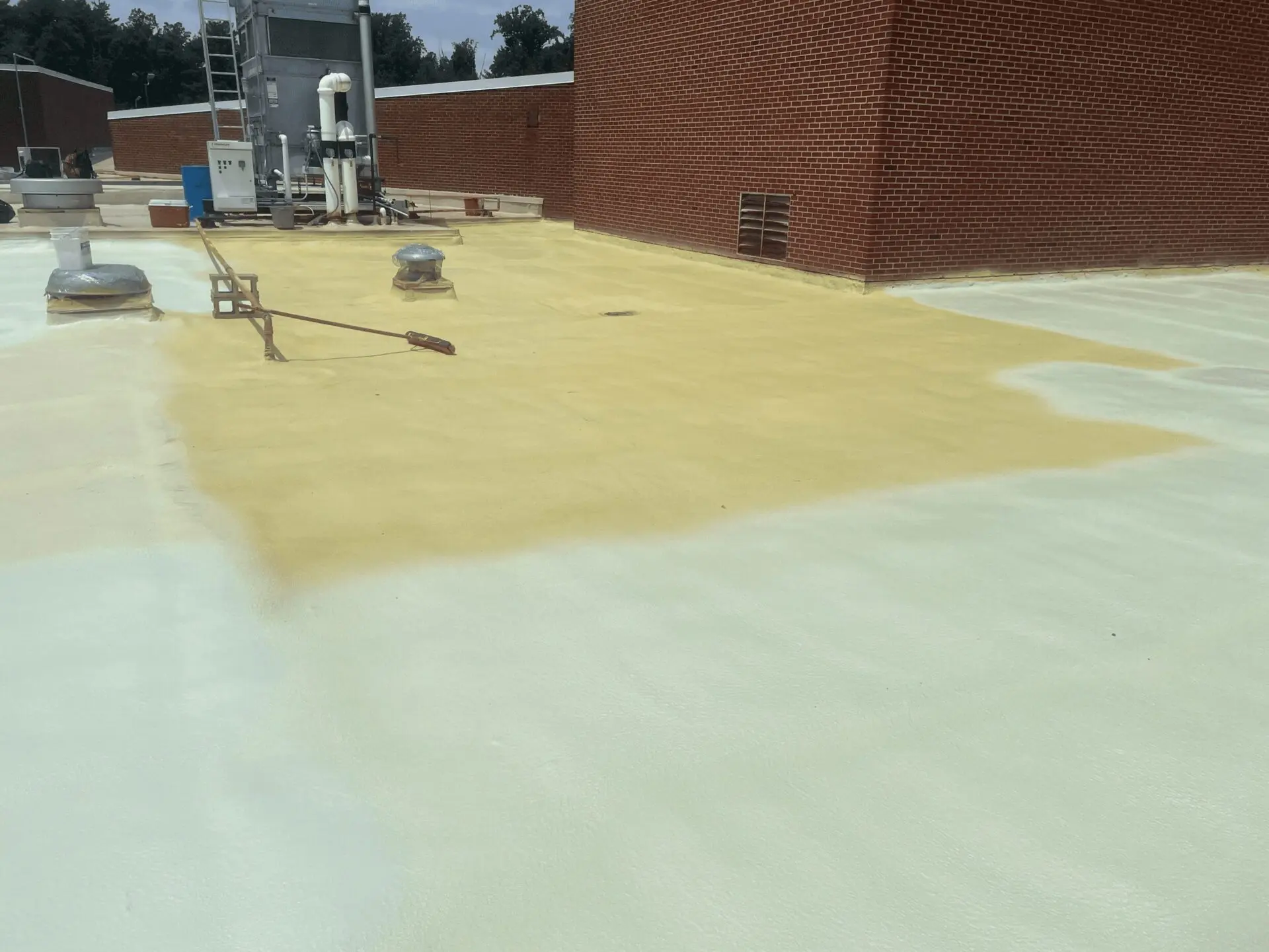 Workers applying a protective coating on a rooftop surface.