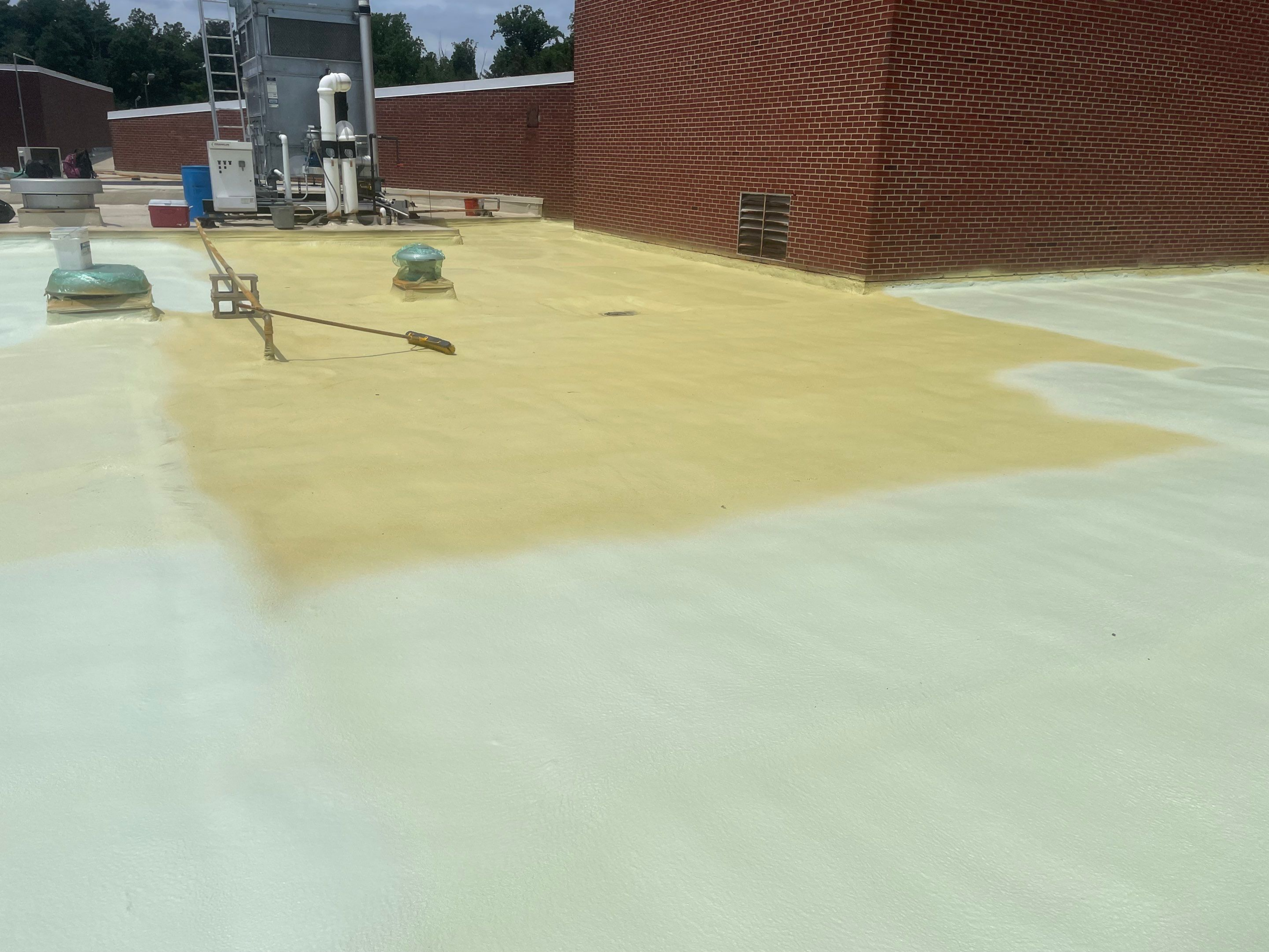 Workers applying a protective coating on a rooftop surface.