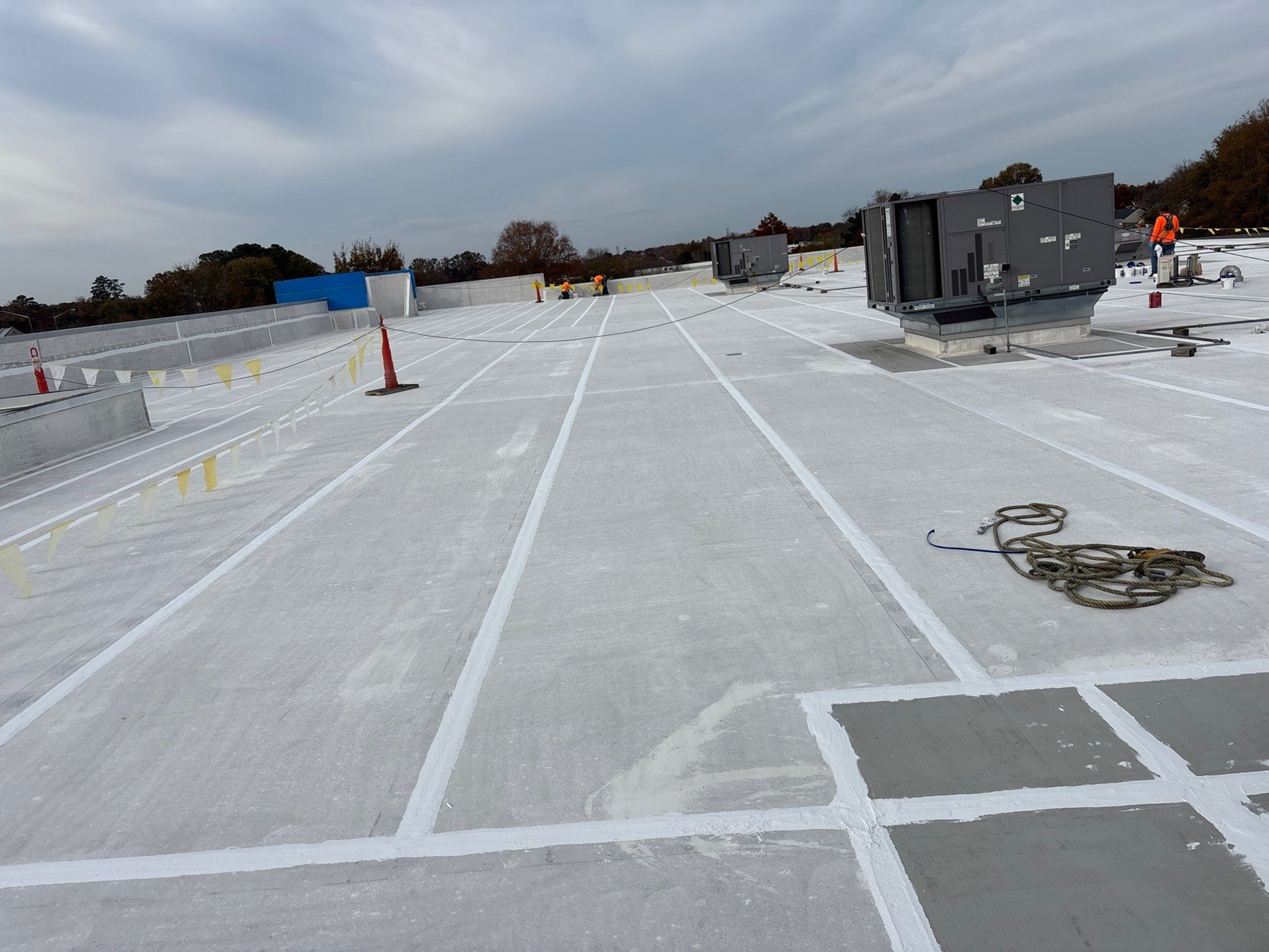 A freshly coated flat roof with marked sections under a cloudy sky.