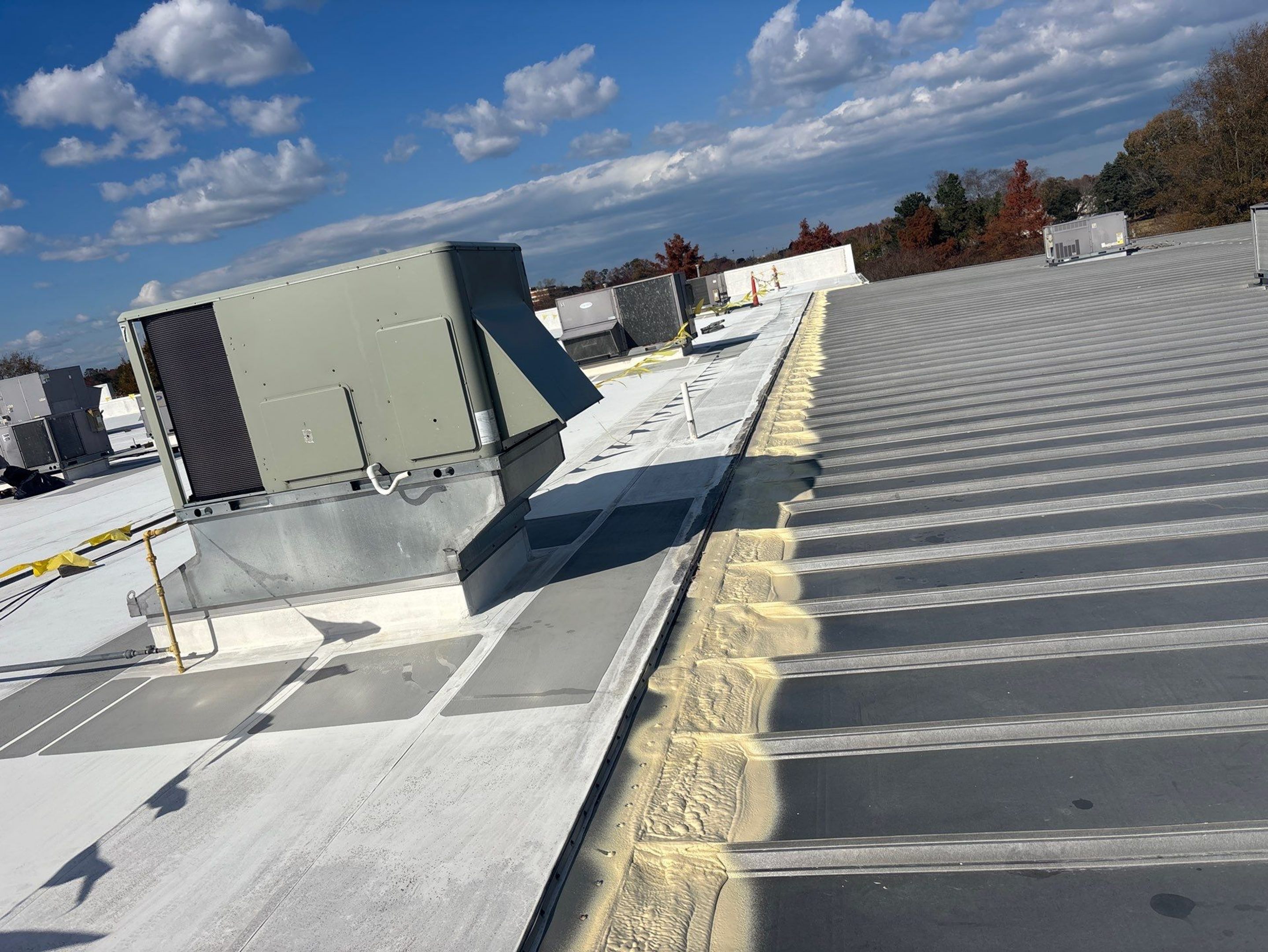 A rooftop with HVAC units and insulation along the edges under a blue sky.