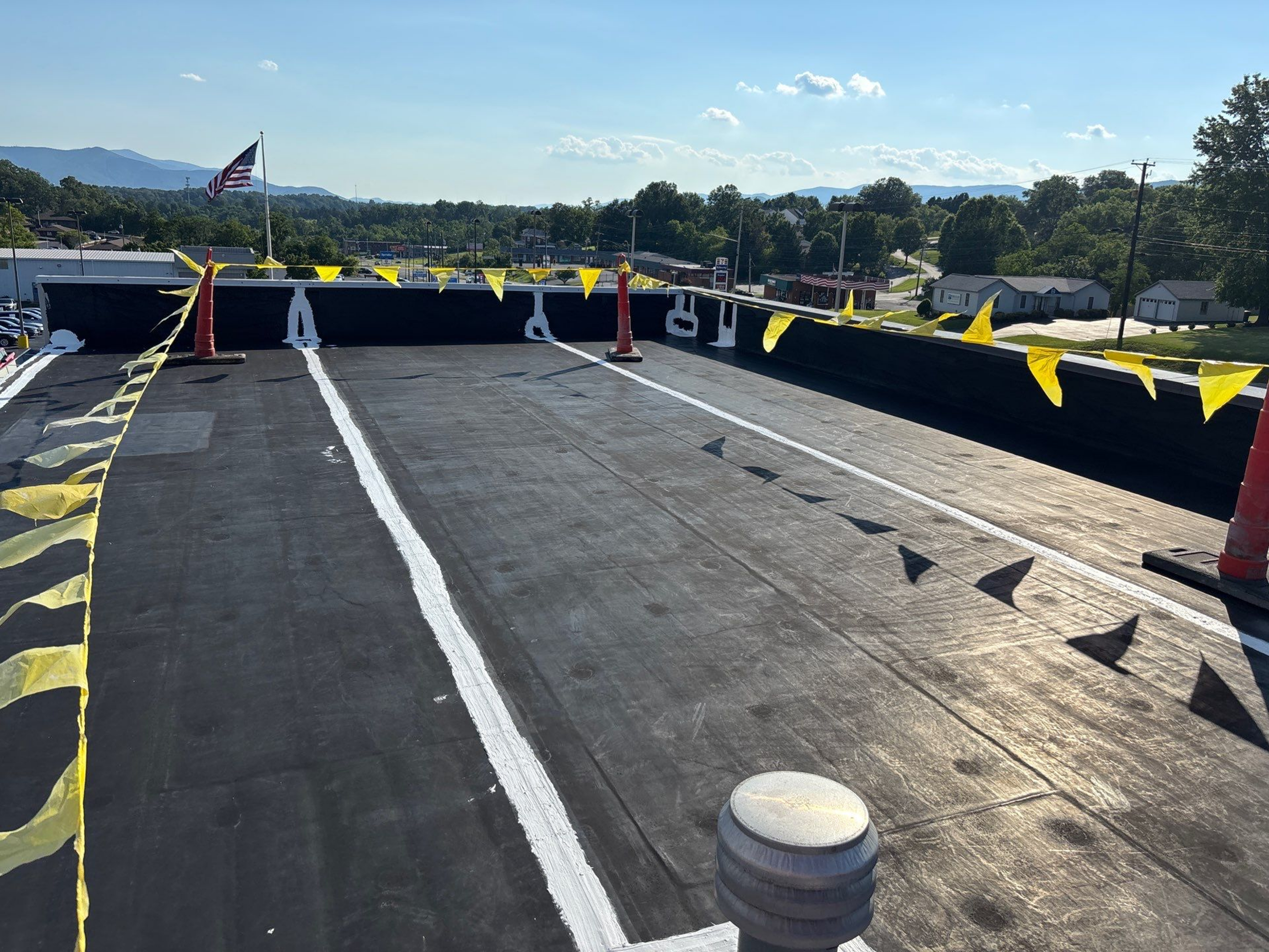 A flat rooftop with waterproofing and drainage elements under clear skies.