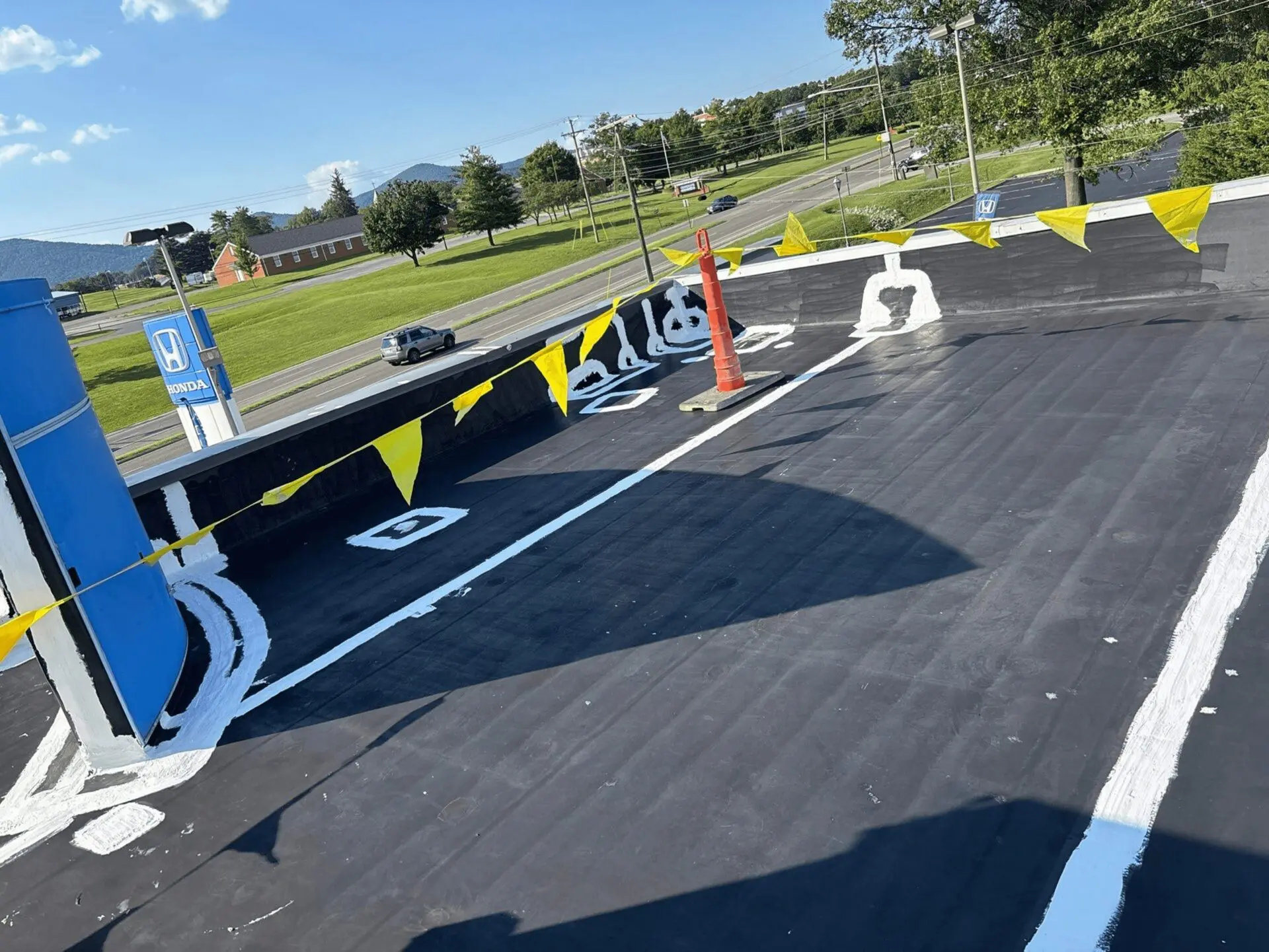 A freshly painted blacktop parking area with handicap spaces and safety cones.