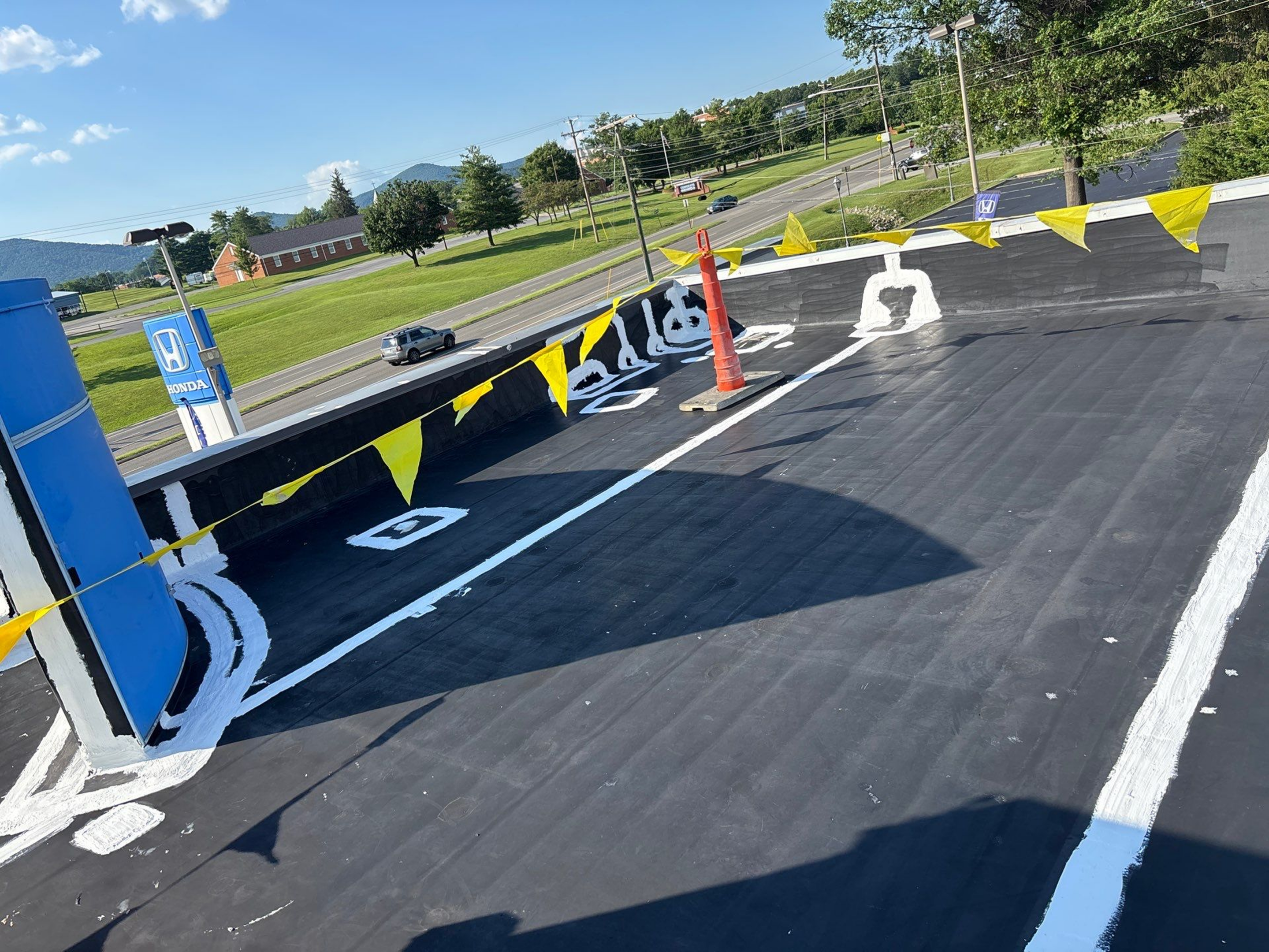 A freshly painted blacktop parking area with handicap spaces and safety cones.